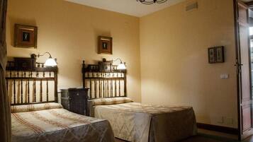 A room with two beds, a chandelier, and framed pictures on the walls.