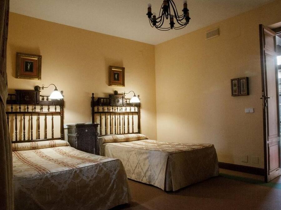 A room with two beds, a chandelier, and framed pictures on the walls.