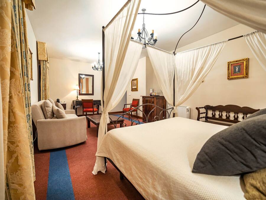 Un dormitorio con una cama con dosel, un sofá, un escritorio y una silla.