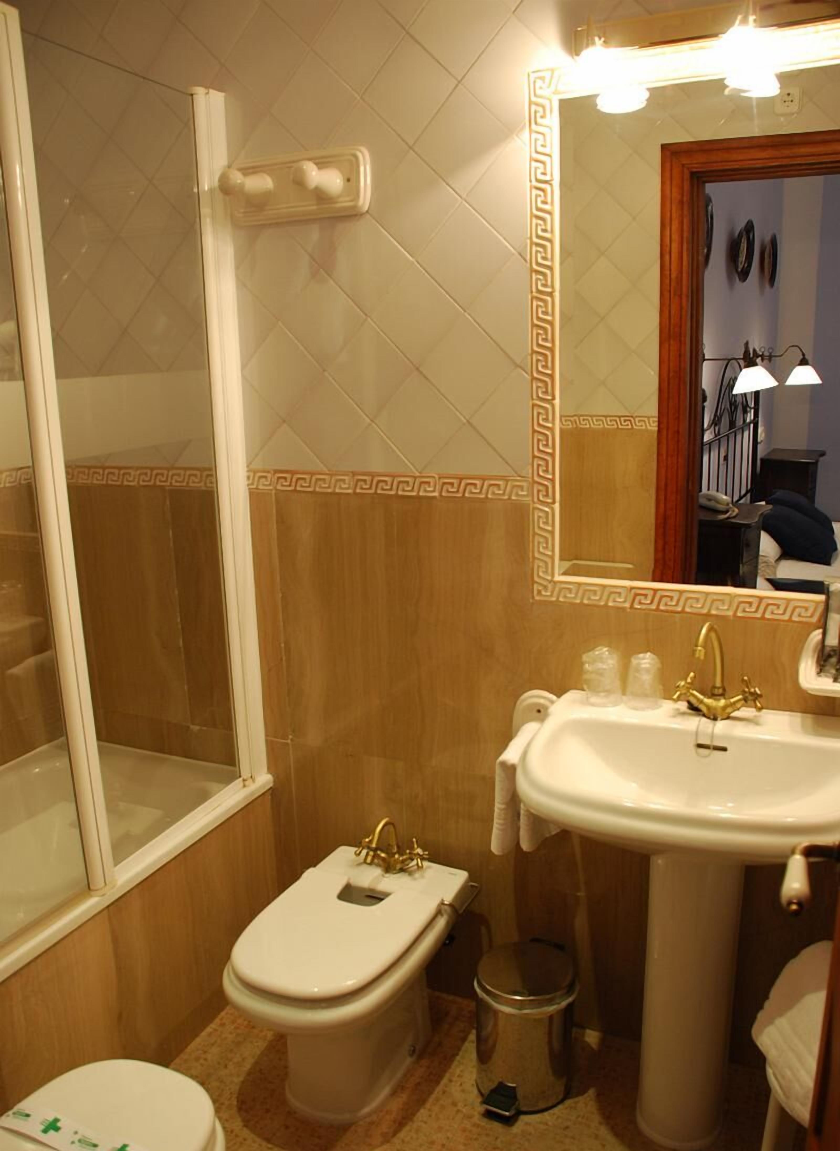 Ein Badezimmer mit Dusche, Toilette, Waschbecken und einem beleuchteten Spiegel.