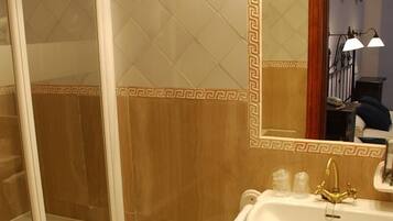 Ein Badezimmer mit Dusche, Toilette, Waschbecken und einem beleuchteten Spiegel.
