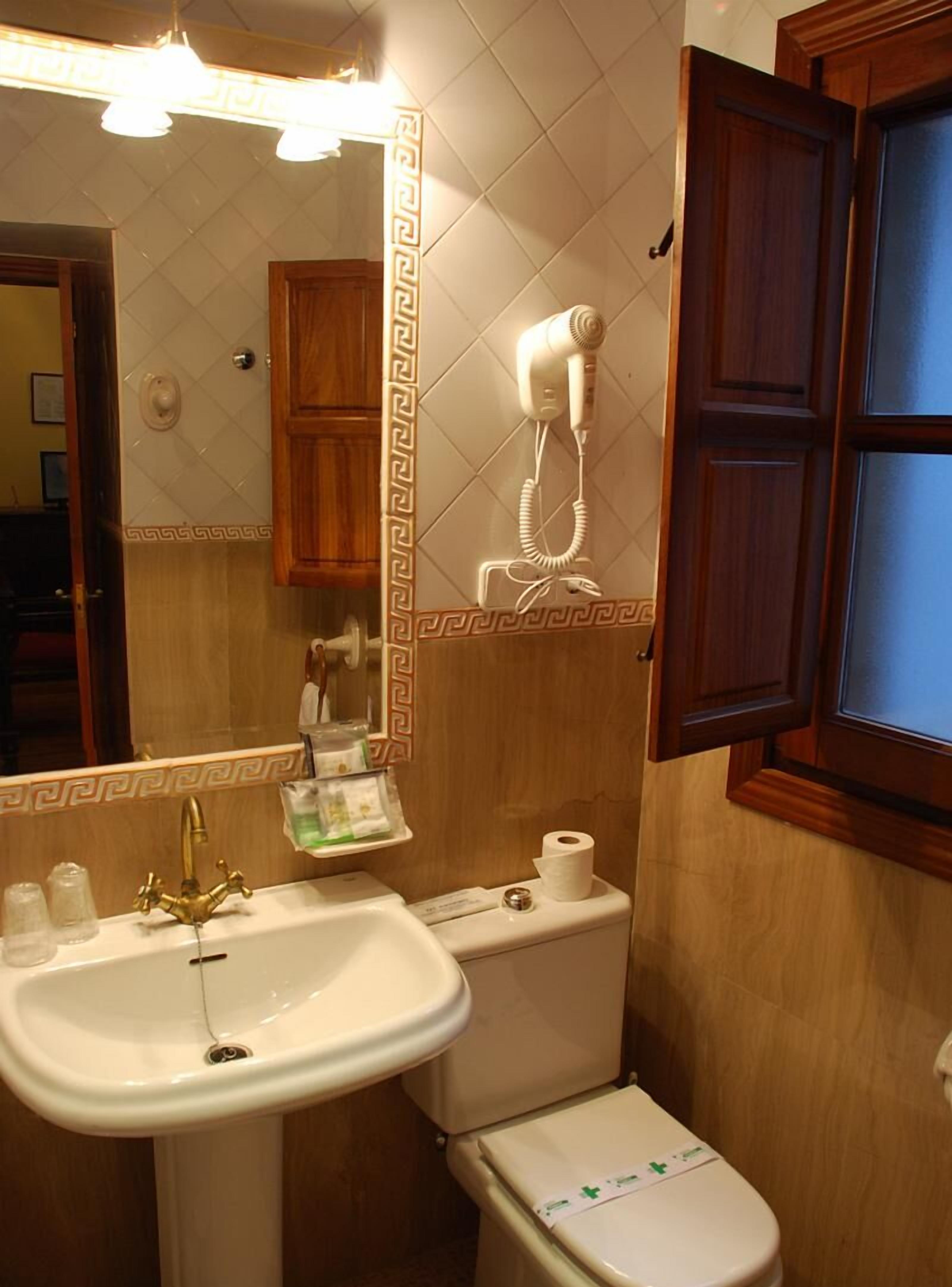 Un baño con lavamanos, inodoro y secador de pelo montado en la pared.