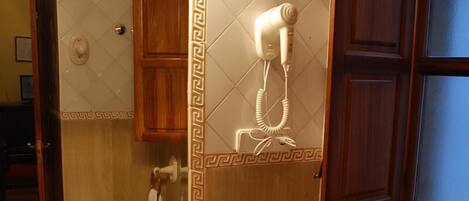 A bathroom with a sink, toilet, and a hairdryer mounted on the wall.