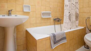 Un baño con bañera, lavabo, espejo y cortina de ducha.