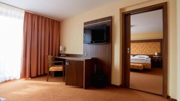 A hotel room with a desk, chair, television, and a bed.
