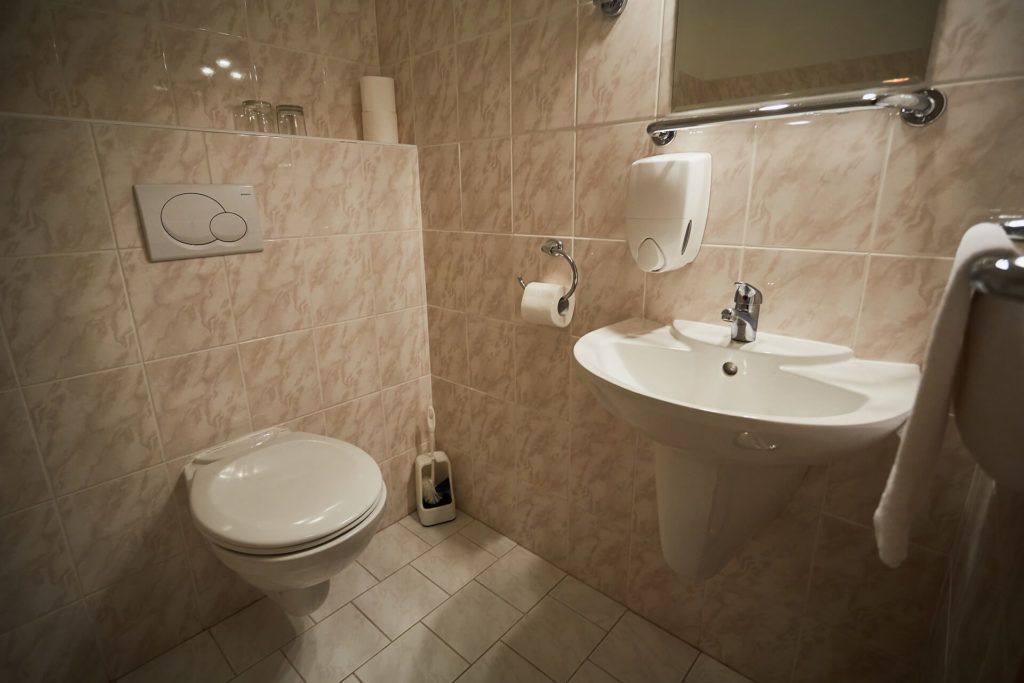 A bathroom with a toilet, sink, and hand dryer.