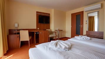 Une chambre d’hôtel avec deux lits, un bureau, une chaise, une télévision et une petite table.