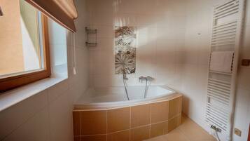 A modern bathroom with a freestanding bathtub, a window with a brown blind, and a towel rack.