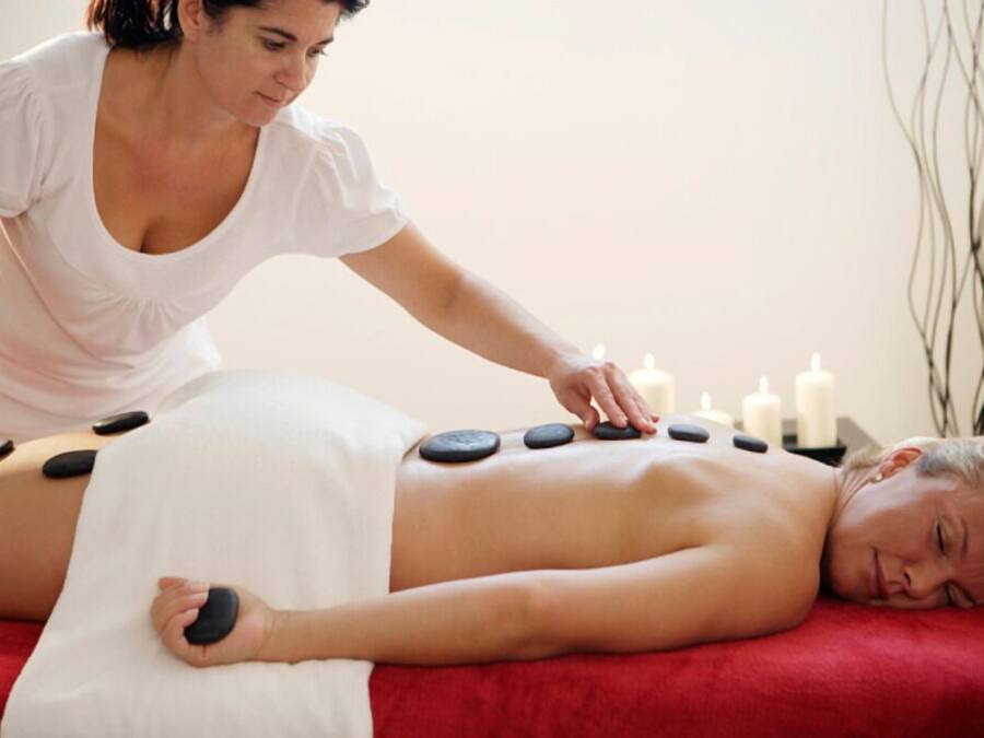 Une personne reçoit un massage aux pierres chaudes, les pierres étant placées sur son dos.