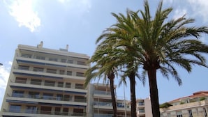 Un immeuble à plusieurs étages, doté de balcons, d’une pharmacie et de voitures garées.