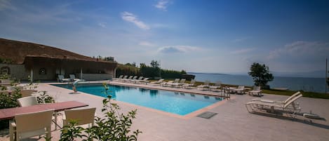 Una piscina al aire libre de temporada, sillones reclinables de piscina