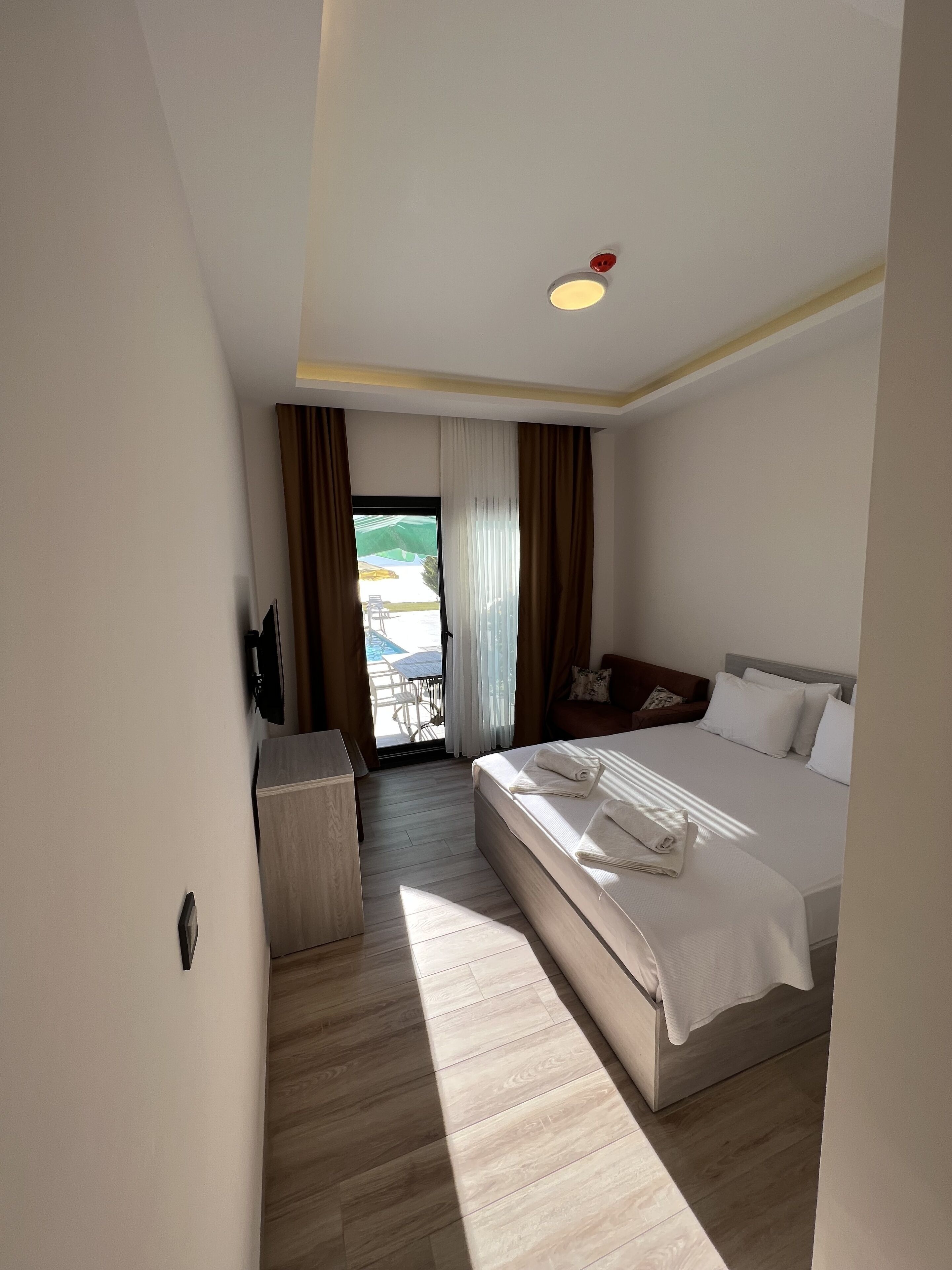A hotel room with a bed, a desk, and a view of the outdoors.