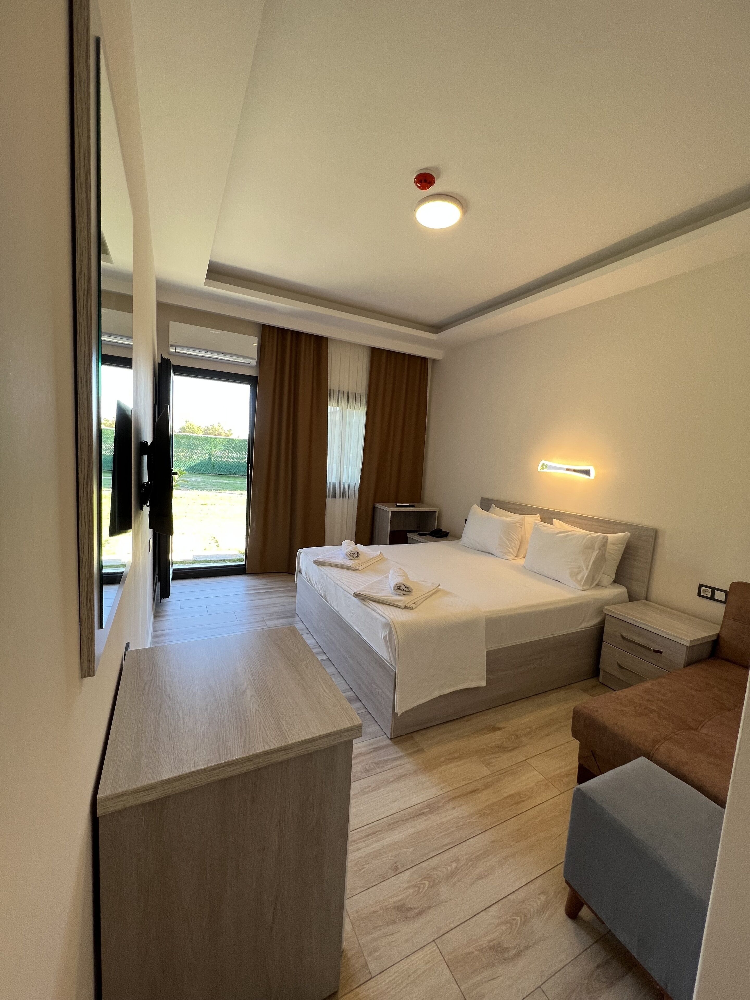 Habitación de hotel con cama, mesitas de noche, escritorio y vistas al exterior.