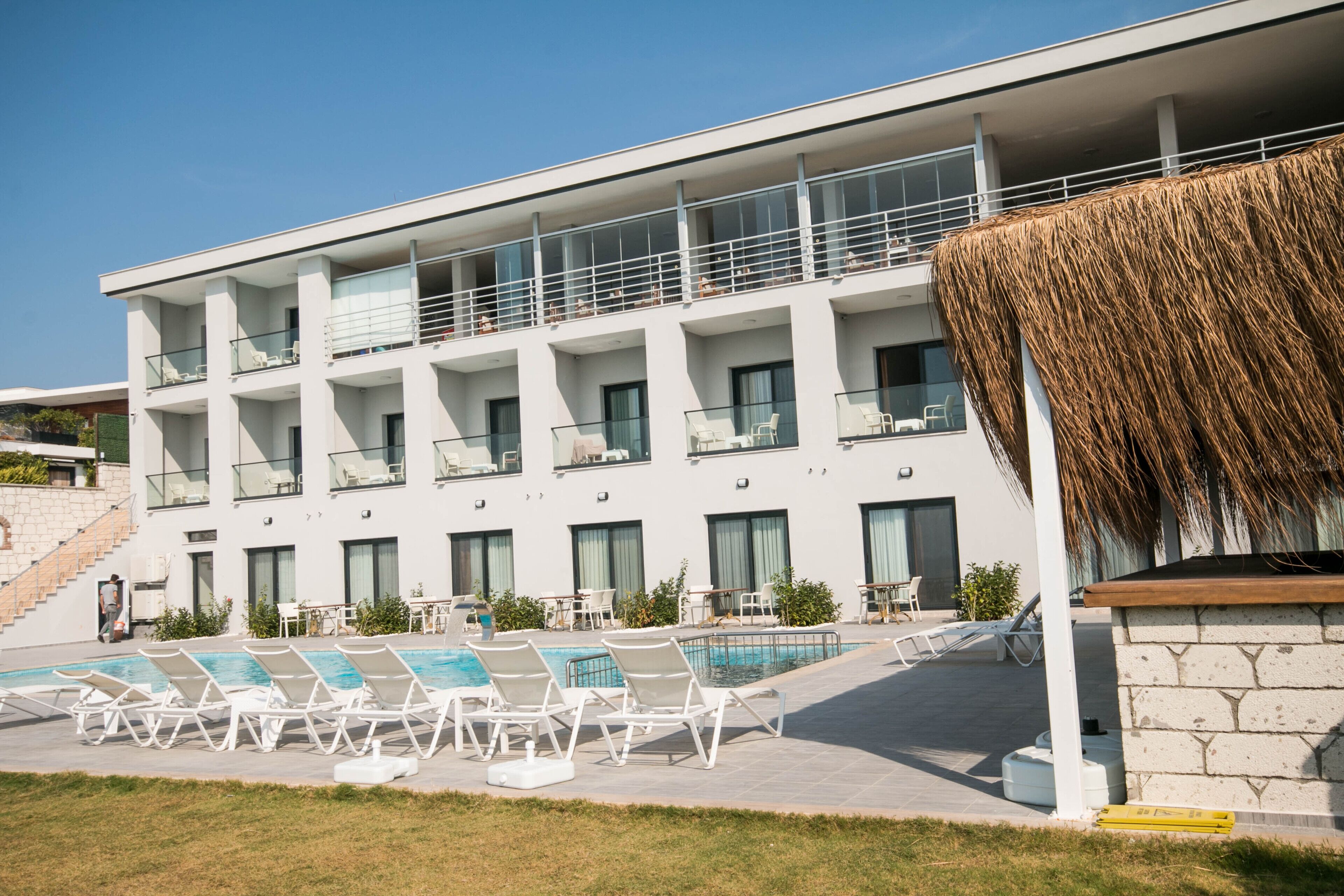 Ein modernes Hotel mit Poolbereich, mehreren Balkonen und einem Dach aus Schilf.