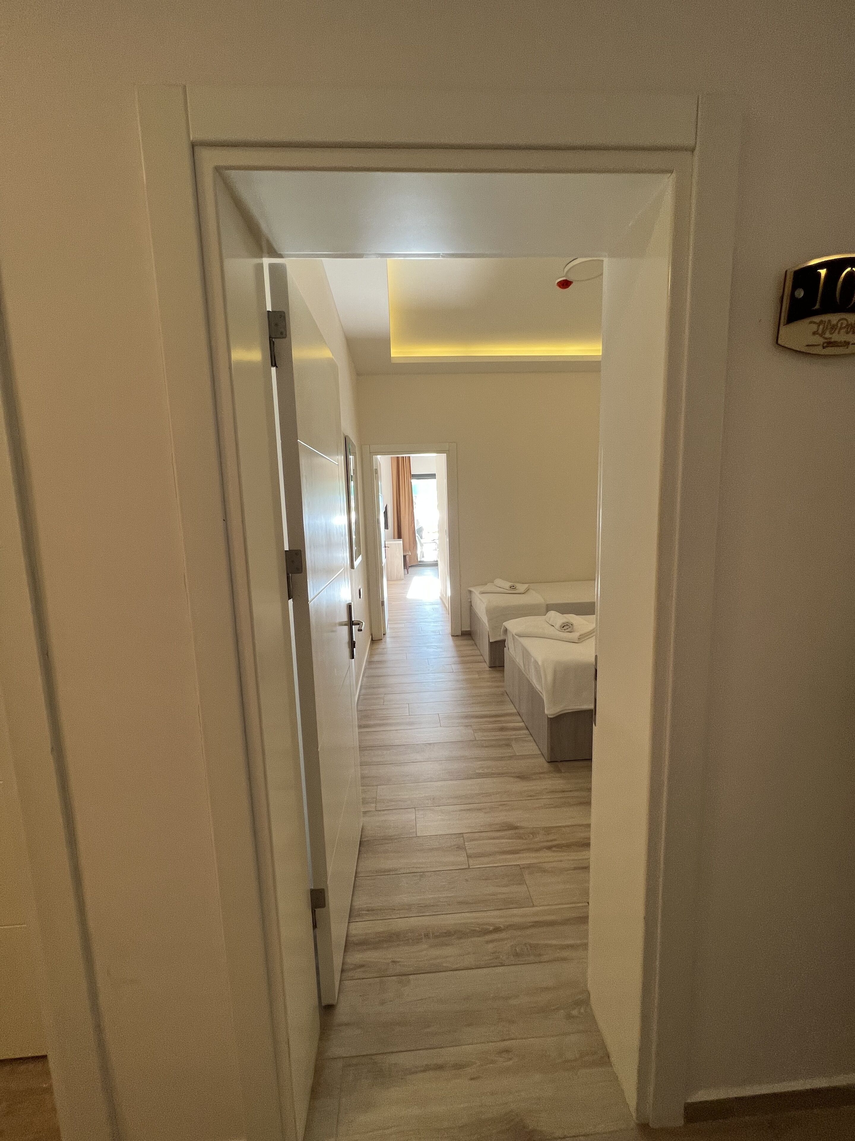A hallway leading to a bedroom with a bed and a nightstand.