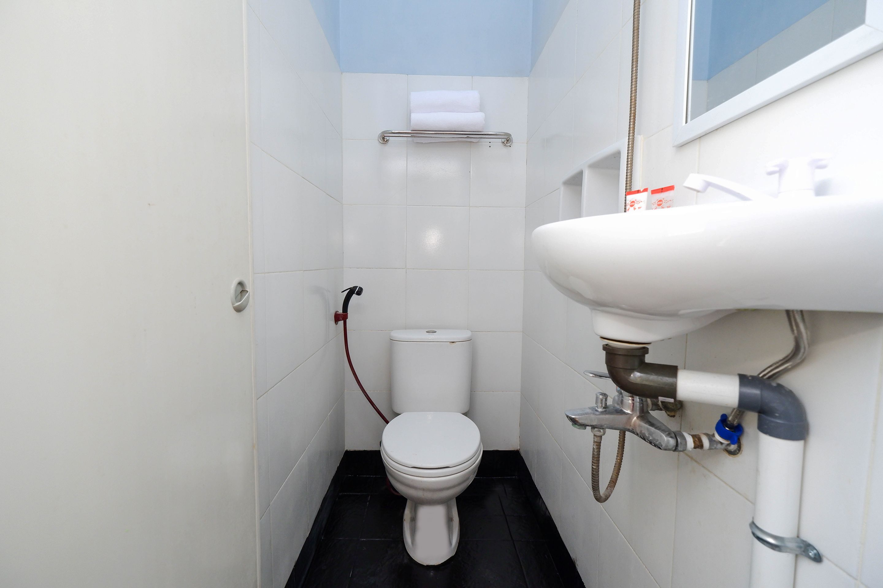 Casa de banho pequena e limpa, com sanita, lavatório e porta-toalhas.