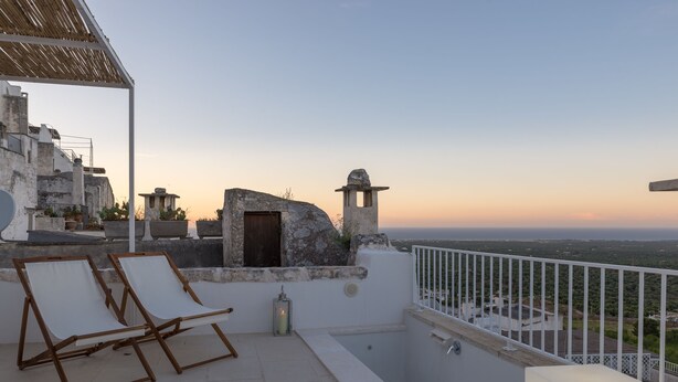 Una terraza en la azotea con dos sillones de descanso, una piscina pequeña y vistas al paisaje.