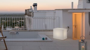 Una terraza en la azotea con piscina, una puerta y un farol.
