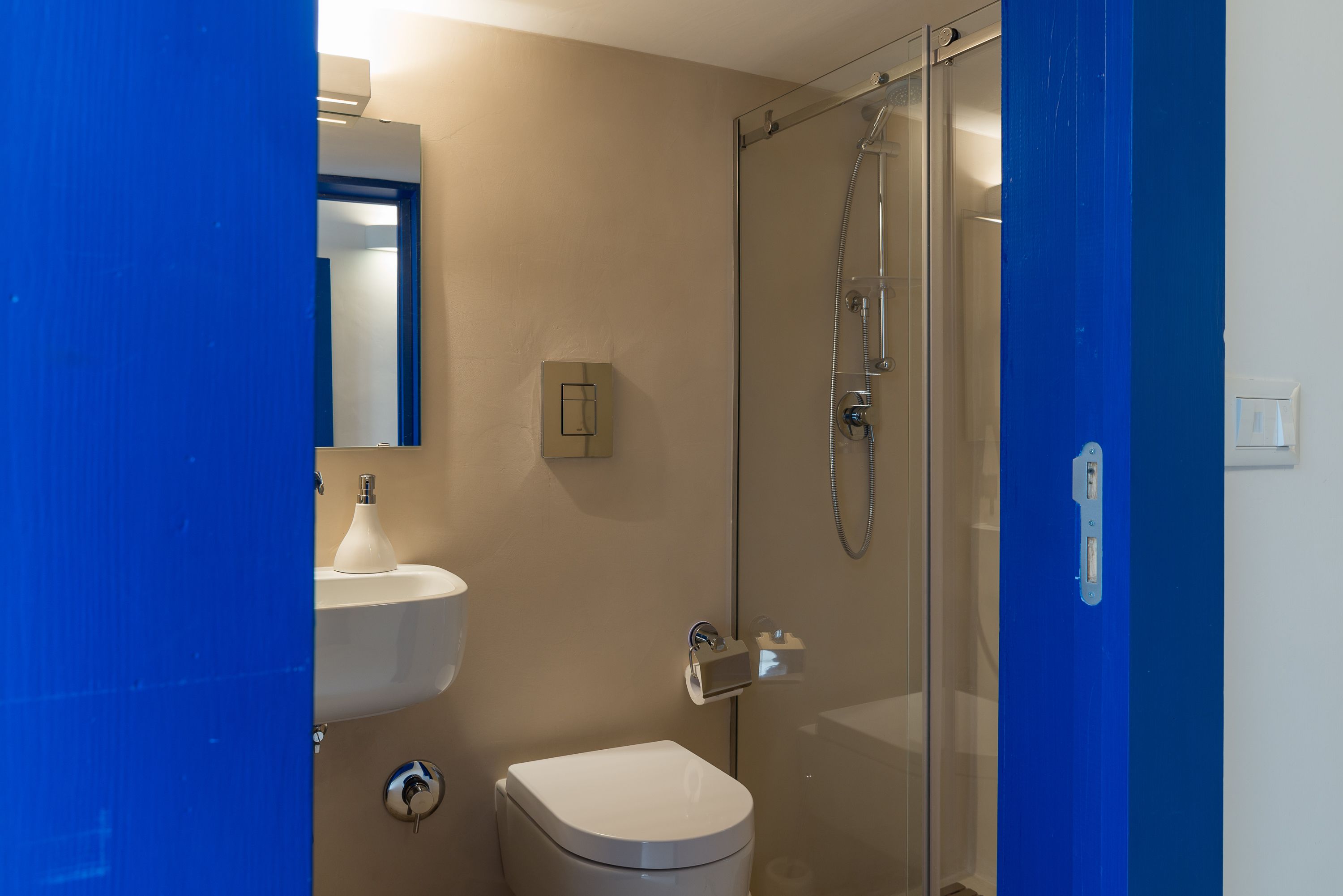 Een badkamer met een douchecabine van glas, een wit wastafelmeubel en een toilet.