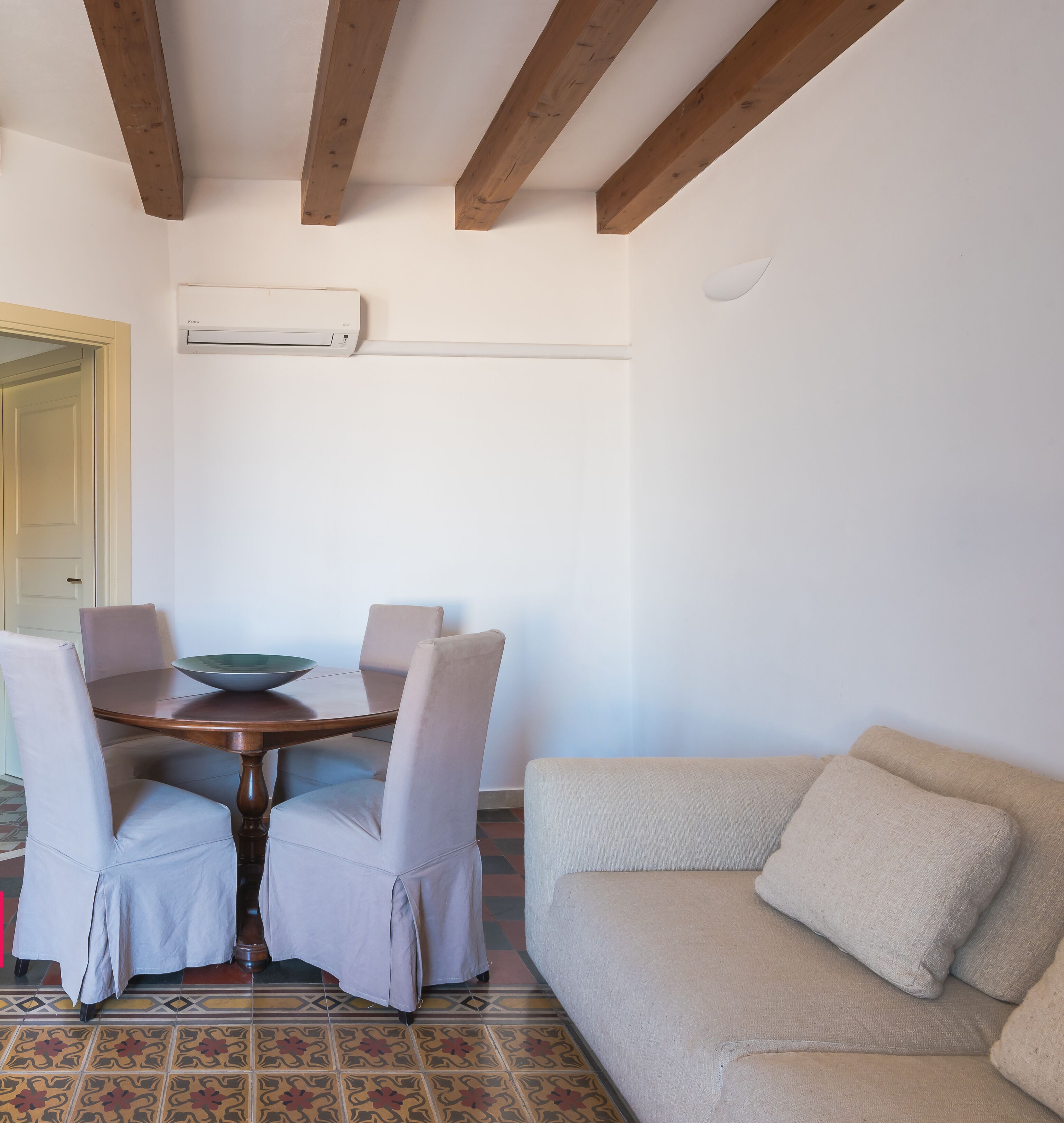 Un comedor con una mesa de madera, cuatro sillas, un bol y un sofá color beige.