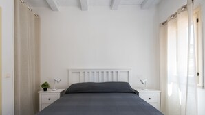 Ein Schlafzimmer mit einem Bett, zwei Nachttischen, einer Lampe und einer kleinen Pflanze.