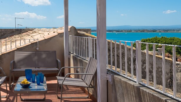 Eine Terrasse mit Meerblick, Sitzgelegenheiten im Freien und einer Pergola.