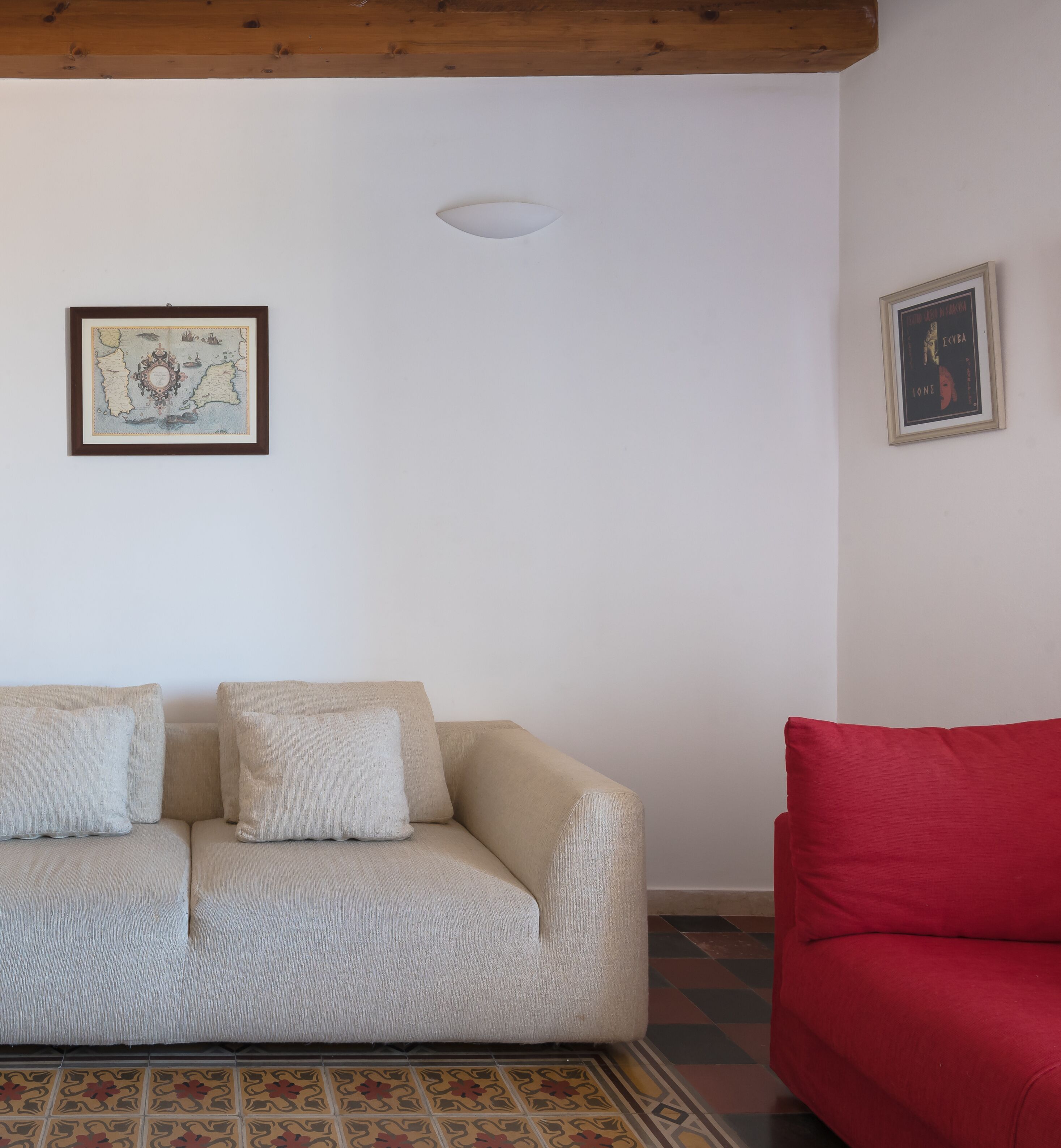 A living room with a beige sofa, a red armchair, and a patterned rug.