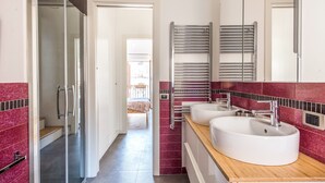 A modern bathroom with two sinks, a glass shower enclosure, and a red-tiled backsplash. - Terrazza dei Colori alla Kalsa by Wonderful Italy (Palermo)
