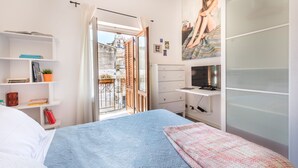 A bedroom with a bed, a wardrobe, a desk, and a balcony with a view of buildings. - Terrazza dei Colori alla Kalsa by Wonderful Italy (Palermo)