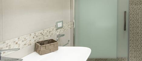 Un baño moderno con cabina de ducha de vidrio, un lavabo blanco y un espejo encima.