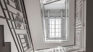 Un escalier orné de rampes en métal travaillées mène à une pièce dotée d’une grande fenêtre.