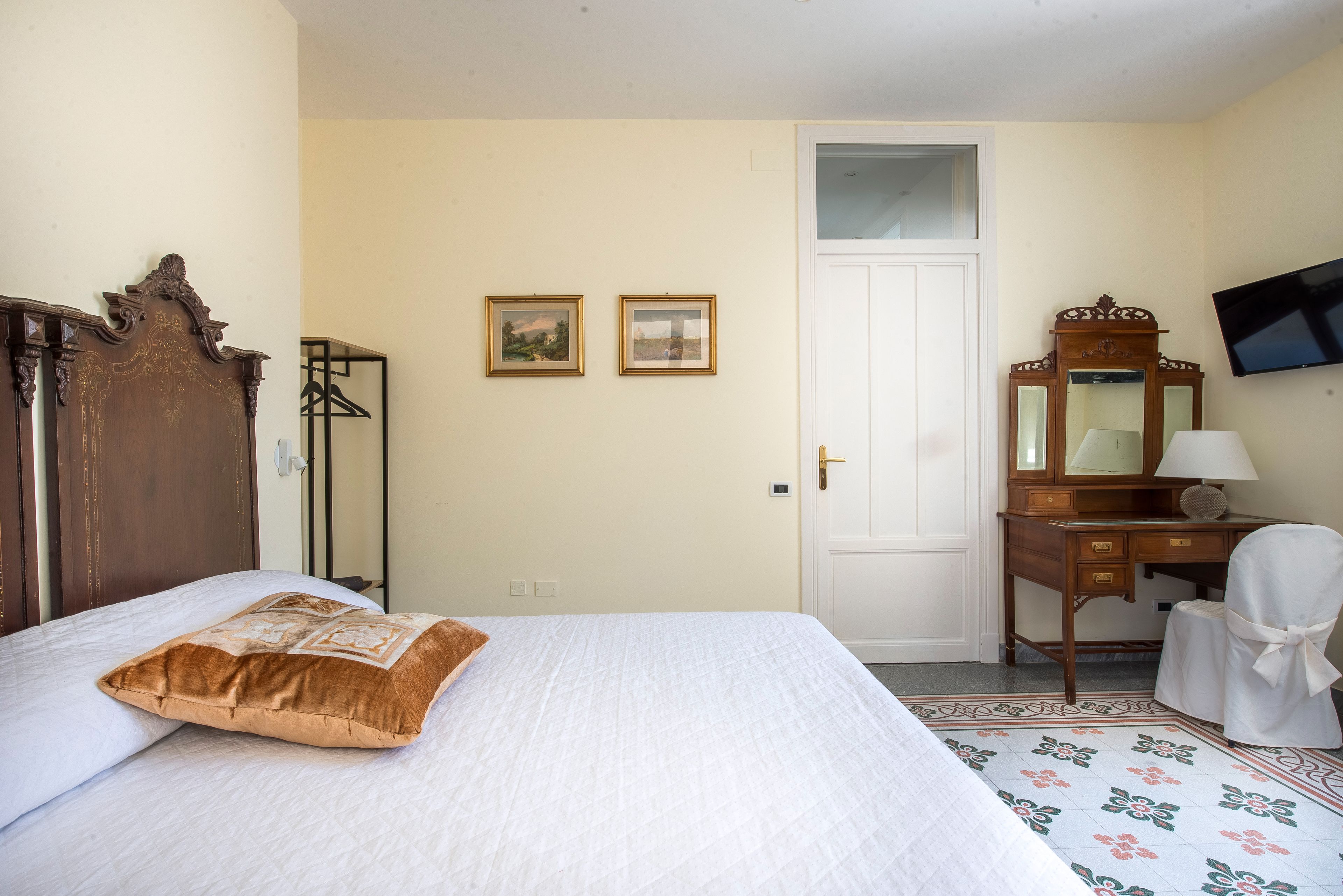 Makuuhuoneessa on sänky, lipasto, peili ja seinälle asennettu televisio.