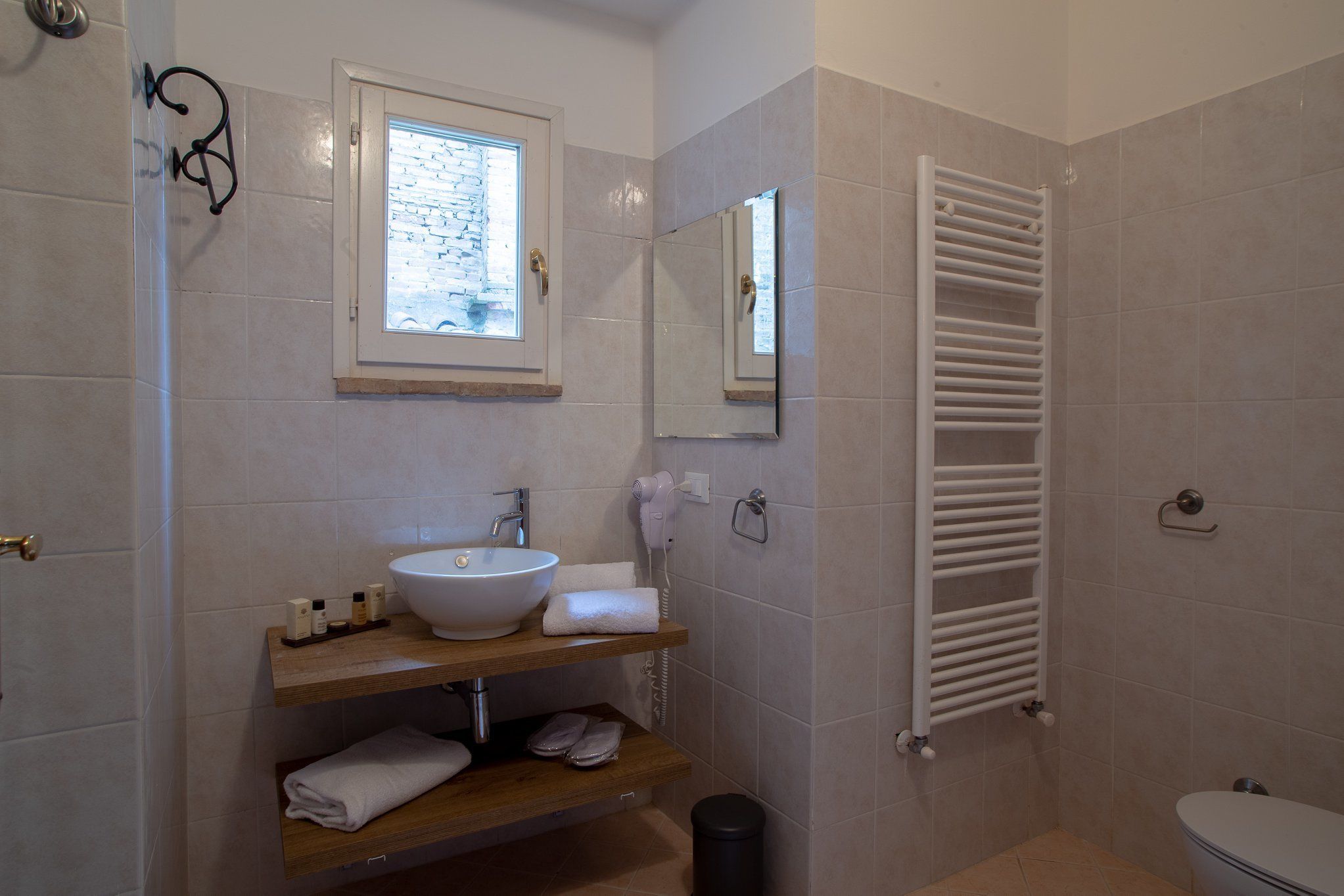 A bathroom with a white sink, mirror, towel rack, and a white toilet.