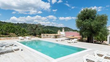 Relax by the serene pool surrounded by lush greenery and comfortable lounge chairs.
