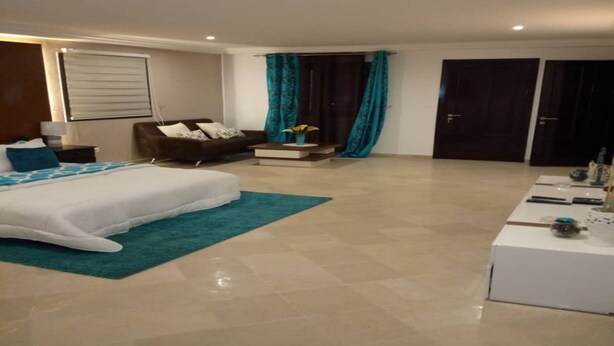 A bedroom with a bed, a sofa, a coffee table, and a TV. - Residence Divine Palace (Abidjan)