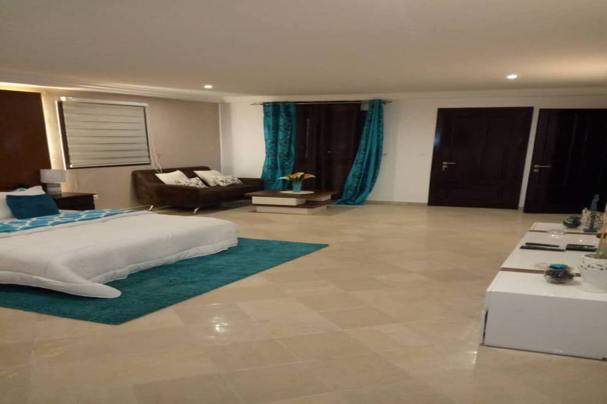 A bedroom with a bed, a sofa, a coffee table, and a TV.