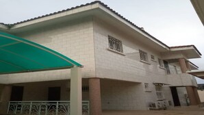 A two-story building with a tiled facade, a covered patio area, and a gated entrance. - Residence Divine Palace (Abidjan)