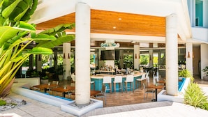 Eine moderne Bar im Freien mit Pool, Holzmöbeln und tropischen Pflanzen.