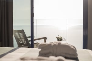 Una habitación de hotel con cama, una silla y vista al mar.