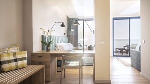 A modern bedroom with a wooden desk, a chair, a bedside table, and a large window offering a view of the outdoors. - Hotel Voramar (L'Escala)