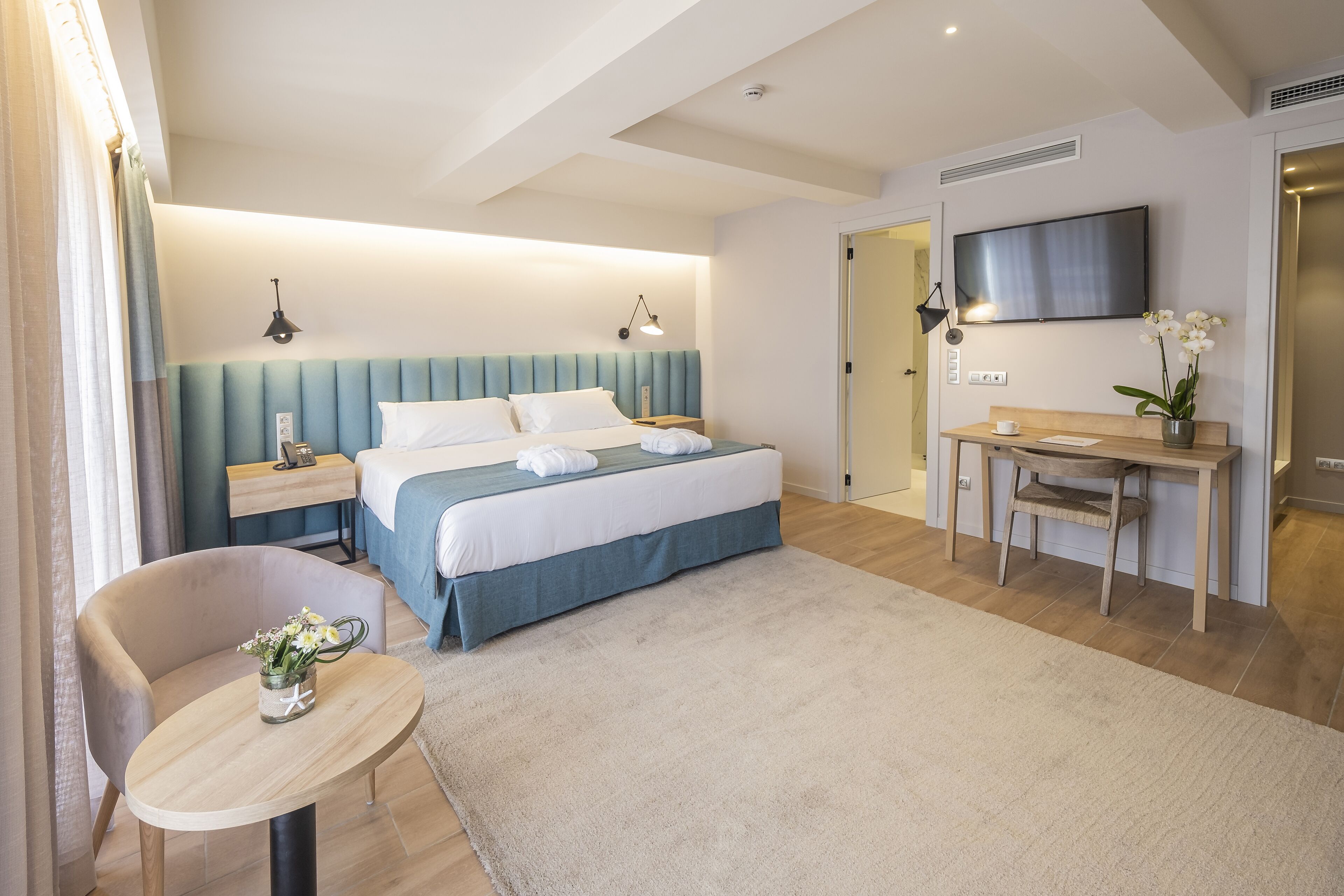Een moderne hotelkamer met een groot bed, een bureau, een stoel en een aan de muur bevestigde televisie.