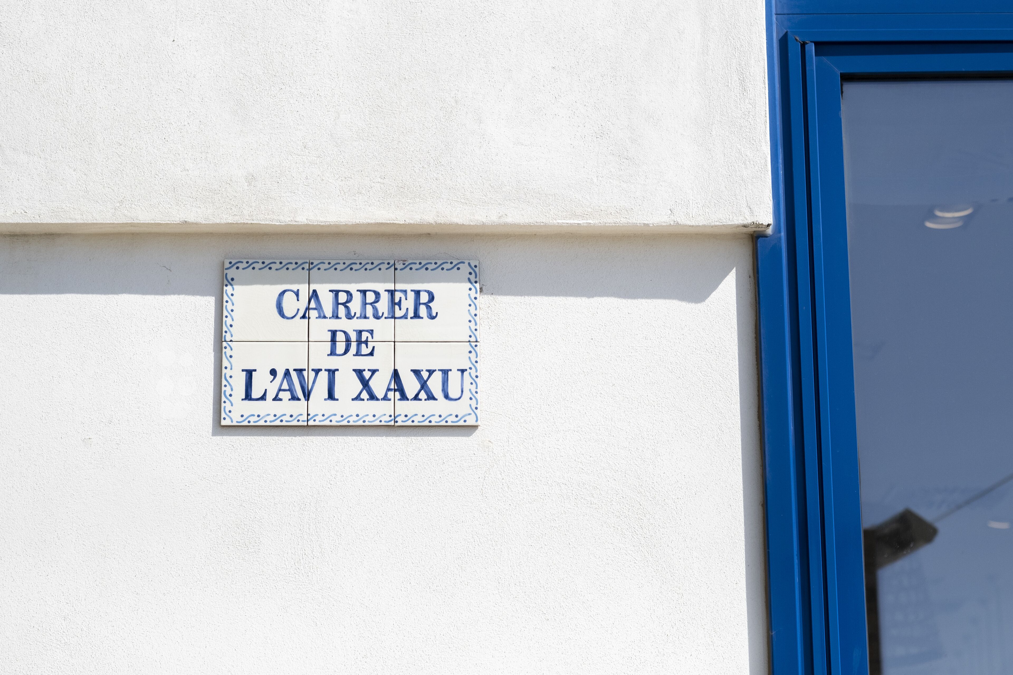 Una señal en un edificio que dice 'CARRER DE L'AVIT XAXU'.