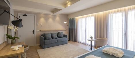 A modern hotel room with a bed, a sofa, a desk, and a chair.