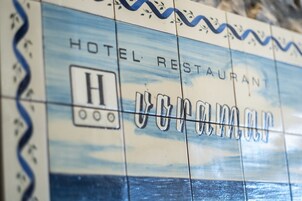 A close-up of a hotel sign with the name "HOTEL RESTAURANT" and a logo with the letter "H".
