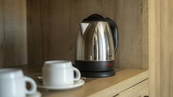 Une machine à expresso en acier inoxydable, posée sur un comptoir en bois, avec une tasse et une soucoupe blanches à côté.