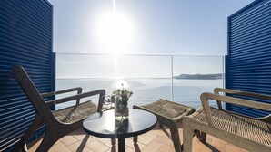 A terrace with a round table and two wooden chairs, overlooking a calm sea and distant land. - Hotel Voramar (L'Escala)