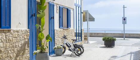 A hotel named "HOTEL VORAMAR" with blue shutters, a white electric bike, and potted plants.