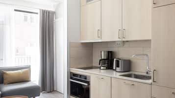 A modern kitchen with light wood cabinets, a built-in oven, a coffee maker, and a toaster.