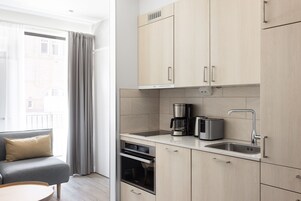 A modern kitchen with light wood cabinets, a built-in oven, a coffee maker, and a toaster.