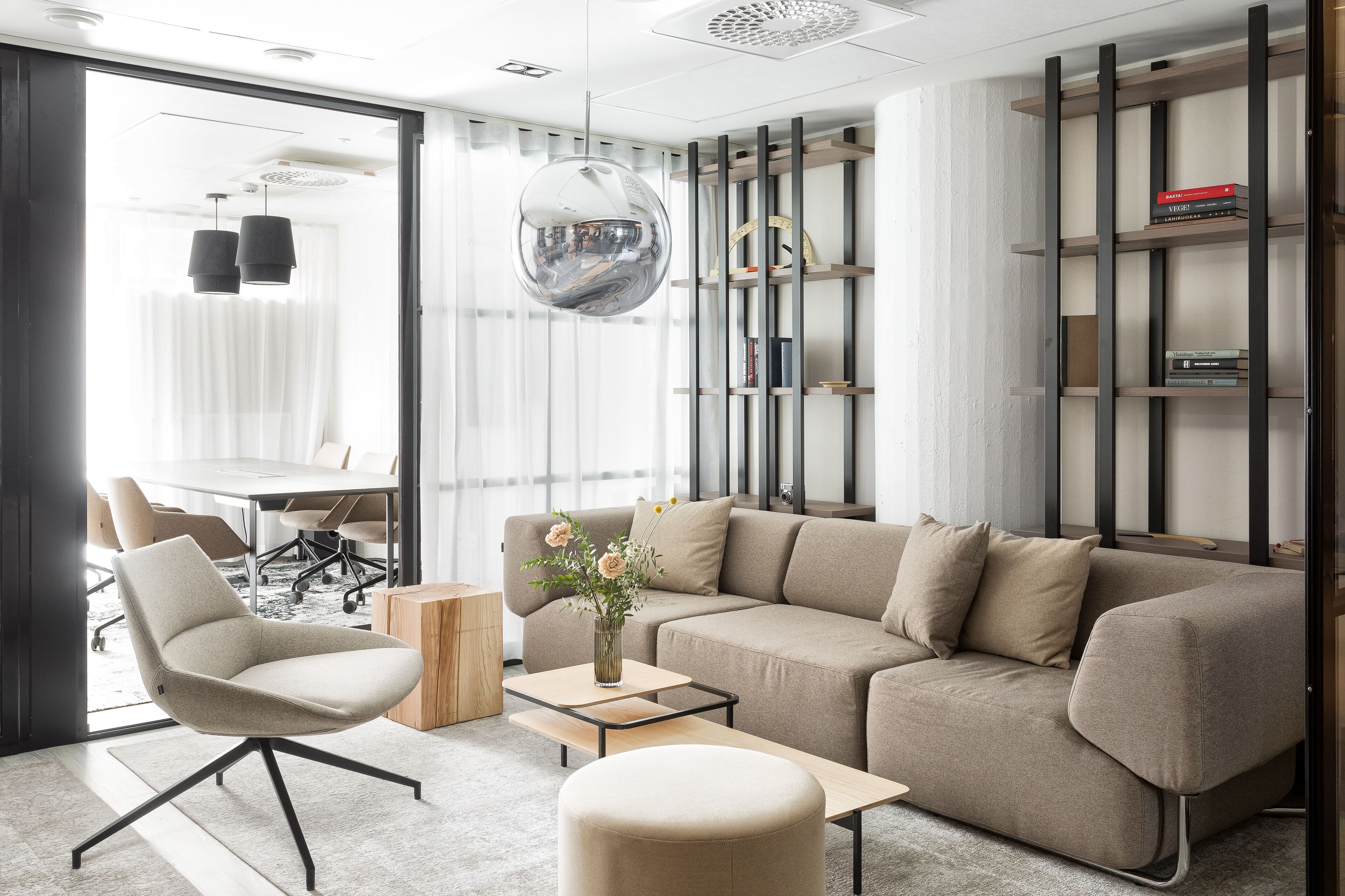 Een moderne woonkamer met een modulaire bank, een ronde salontafel en een boekenkast.